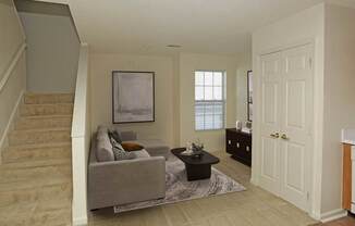 A living room with a couch, a coffee table, and a painting on the wall.