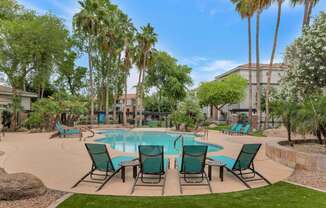 a swimming pool with patio furniture and palm trees