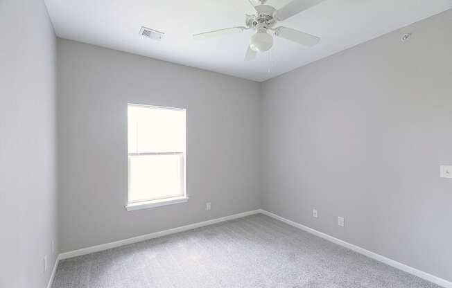 an empty room with a ceiling fan and a window