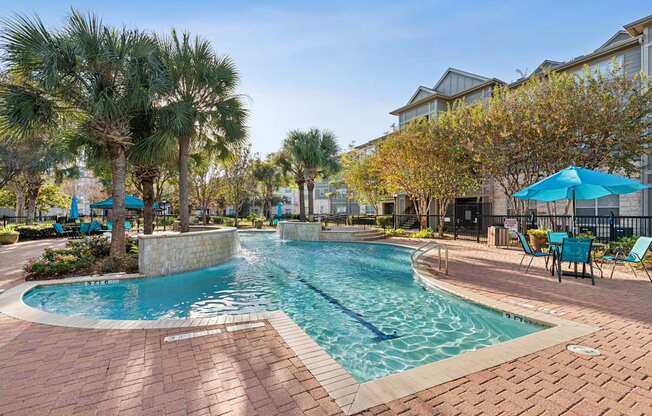 A swimming pool surrounded by palm trees and lounge chairs.