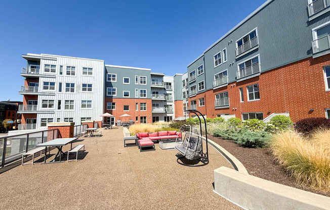 A playground area with a slide and seating area in front of apartment buildings.