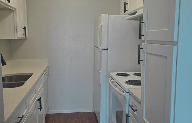 a kitchen with white cabinets and white appliances and a white refrigerator