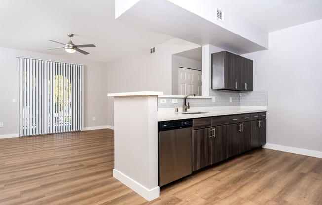 an open living room with a kitchen and a ceiling fan