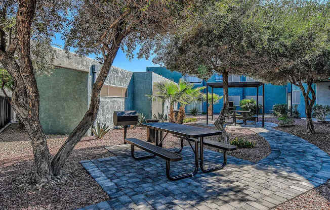 A picnic table is surrounded by trees in a courtyard.