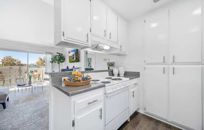 a white kitchen with white cabinetry and a counter top with a basket of fruit