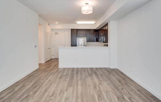 an empty living room with a kitchen in the background