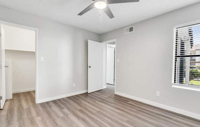 A room with a ceiling fan and a window with blinds.