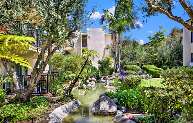 a garden with a pond and palm trees at Willow Tree Apartments, California, 90505