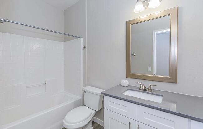 A white bathroom with a toilet, sink, and mirror.