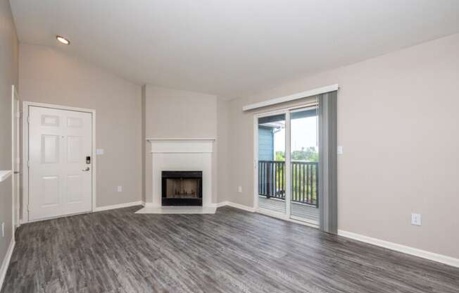 an empty living room with a fireplace and a door to a balcony