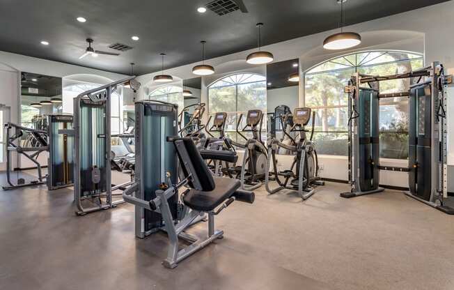 a gym with cardio machines and weights in a building with windows at Mirasol Apartments, Las Vegas, NV 89119