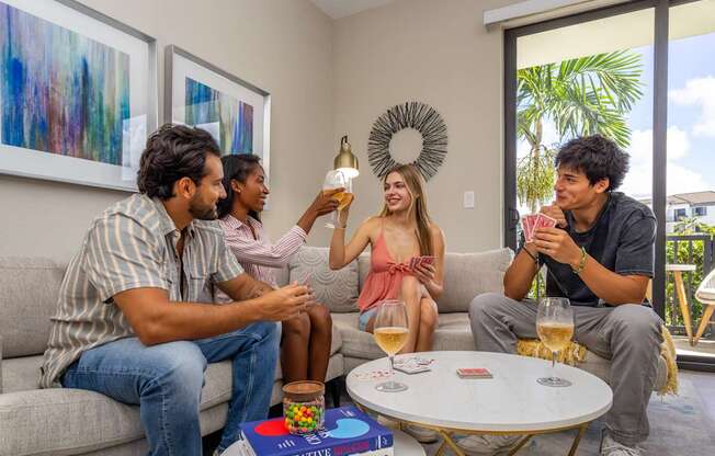 Four people are sitting on a couch and enjoying drinks together.