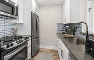 Blue tiled kitchen with stainless steel fridge, oven, and fixtures.