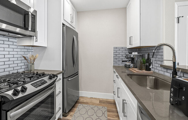 Blue tiled kitchen with stainless steel fridge, oven, and fixtures.