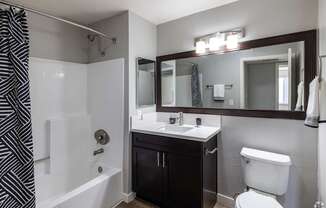 A bathroom with a black and white striped shower curtain.