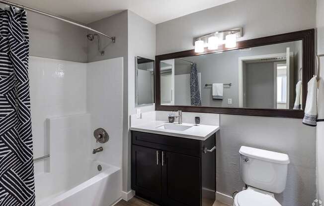 A bathroom with a black and white striped shower curtain.