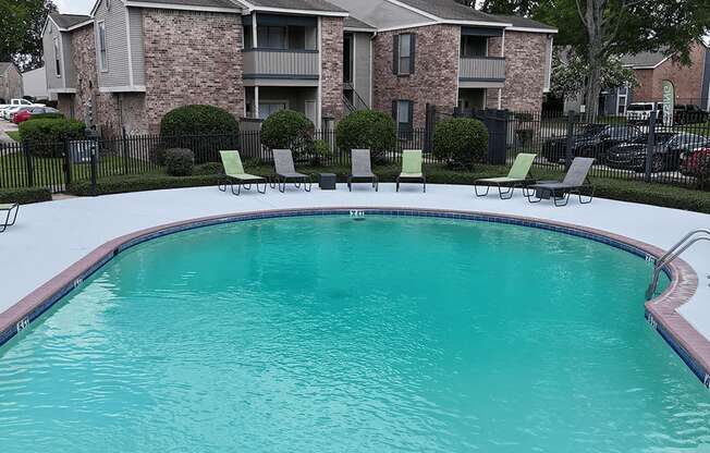 A swimming pool in front of a brick apartment building.