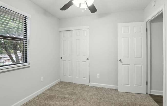 A room with a ceiling fan and two doors.