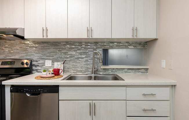 a kitchen with white cabinets and a stainless steel sink
