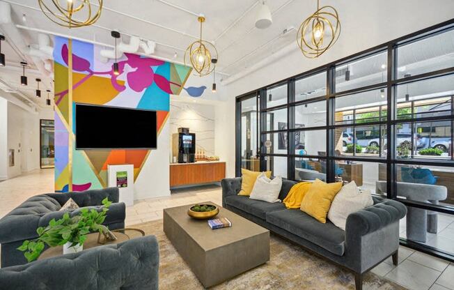 a living room with couches and a tv in a building with glass doors at Link Apartments® 4th Street, North Carolina