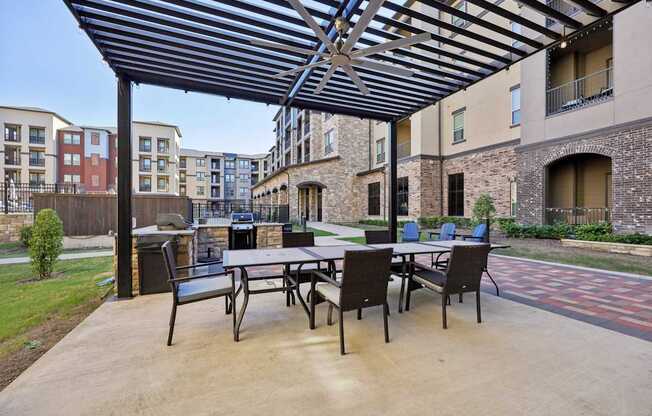 A patio with a table and chairs under a black and white striped awning.