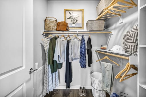 a small walk in closet with a white wall and wooden shelves