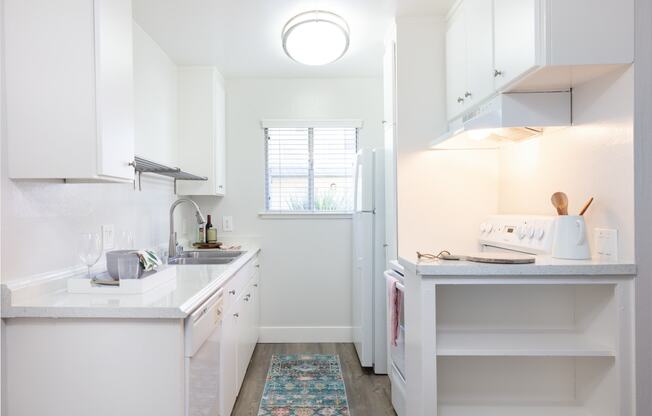 a kitchen with white cabinets and white countertops and a white refrigerator