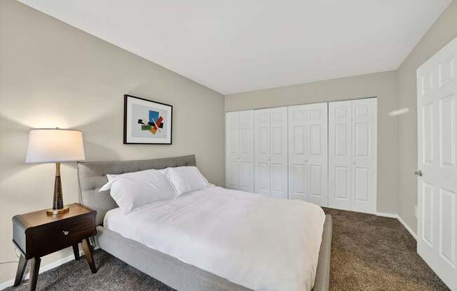 A bedroom with a bed, nightstand, and lamp.