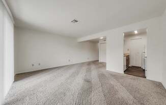 A large, empty room with a carpeted floor and white walls.