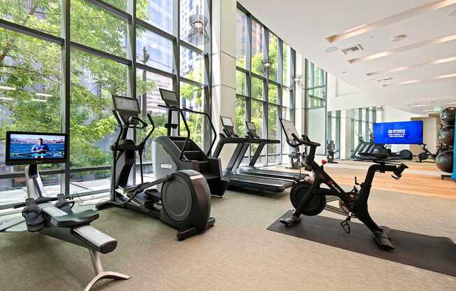 A gym with exercise equipment and a TV screen.