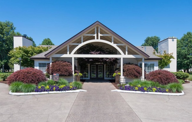 the front entrance of a building with a porch and flowers