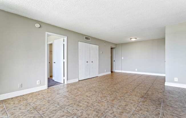 an empty living room with a tile floor and white walls