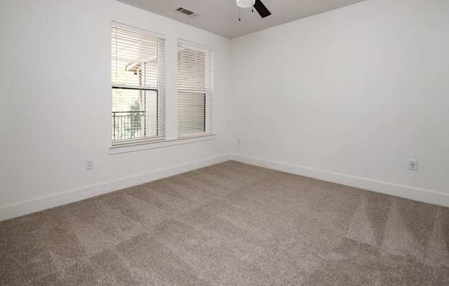 A room with a carpeted floor and a window with blinds.