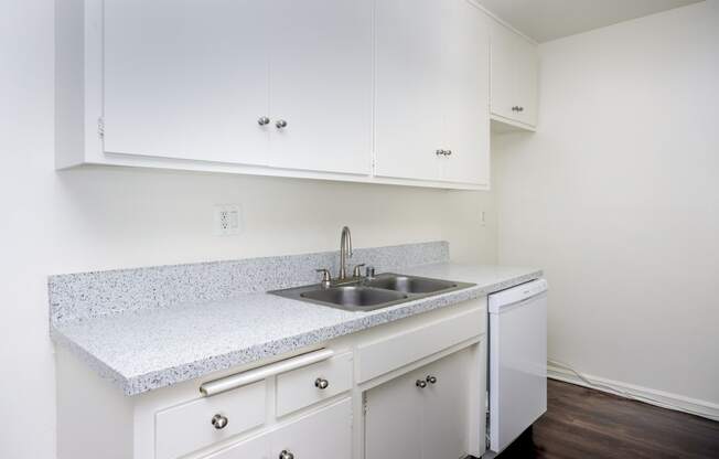 an empty kitchen with white cabinets and a sink