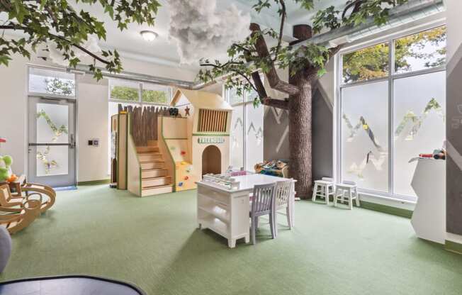 a playroom with a tree in the center of a room with a playhouse at Bakery Living, Pittsburgh, PA