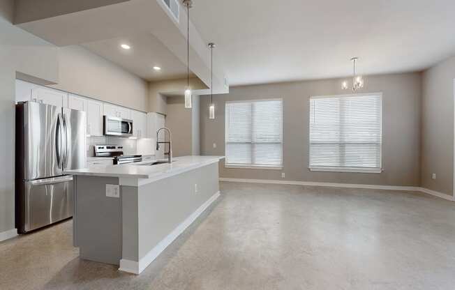 an empty kitchen and living room with a stainless steel refrigerator