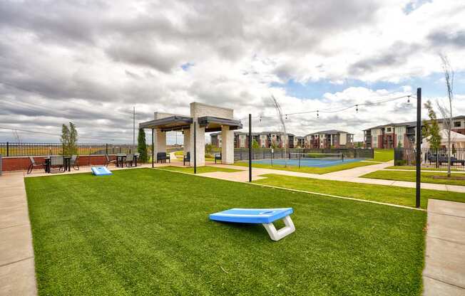 A park with a blue bench and a pool in the background.