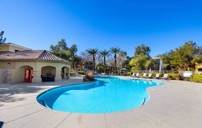 A large outdoor swimming pool with a sun lounger chairs around it.