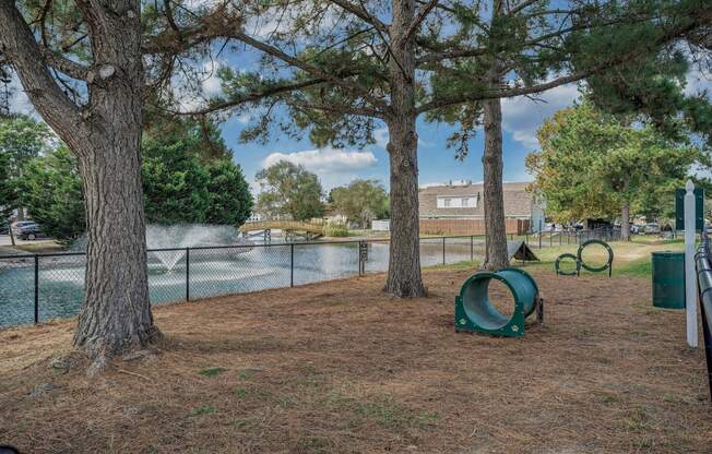 a pet-park with a lake and trees next to it