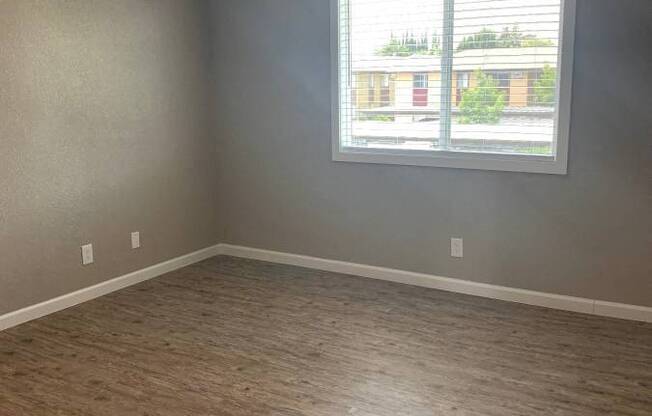 View of living area with wood like flooring, well lit window, veiling fan, and AC