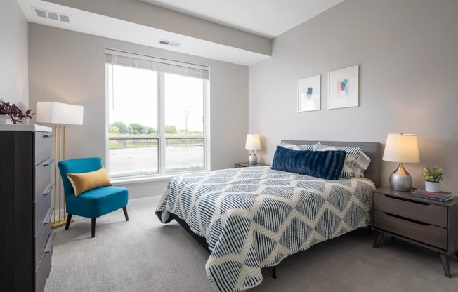 A bedroom with a large bed and a blue chair.