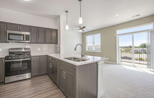 A modern kitchen with dark wood cabinets and stainless steel appliances at Meadowbrooke Apartment Homes in Kentwood, MI 49512
