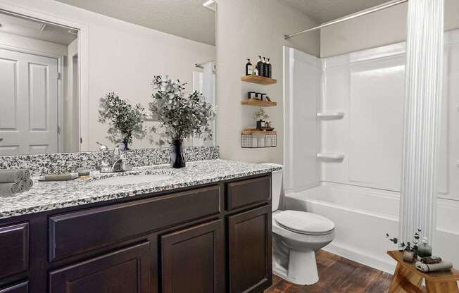 A white bathroom with a dark brown vanity.