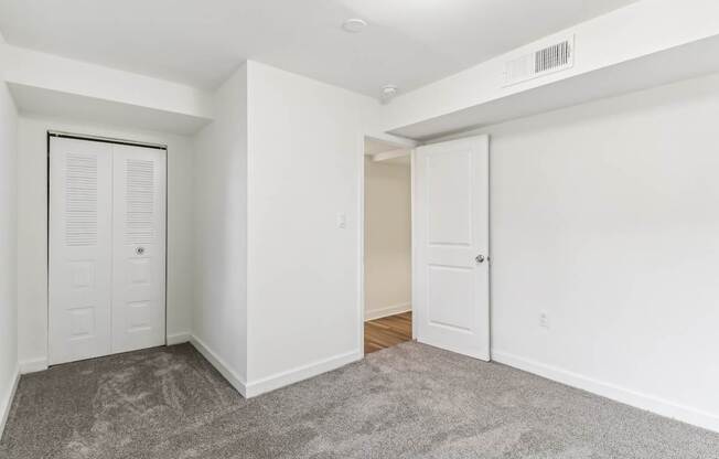 a room with white walls and a carpet and a closet