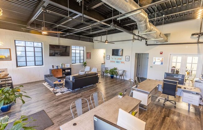 a room with couches and tables with computers on top of them