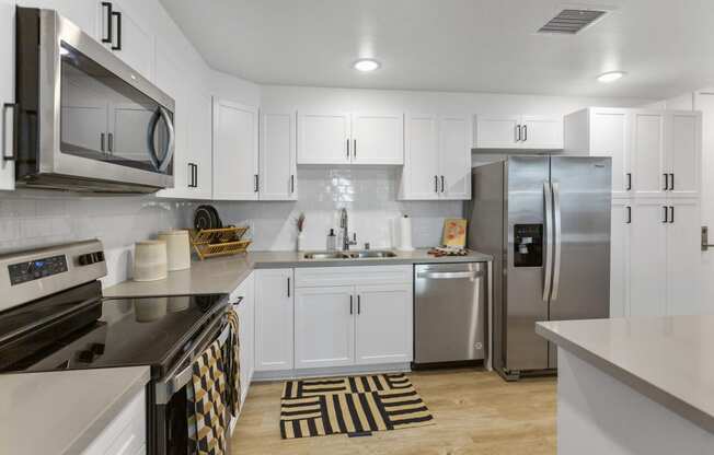 an open kitchen with white cabinets and stainless steel appliances