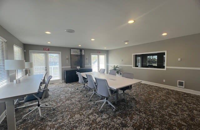 a conference room with a table and chairs and a television