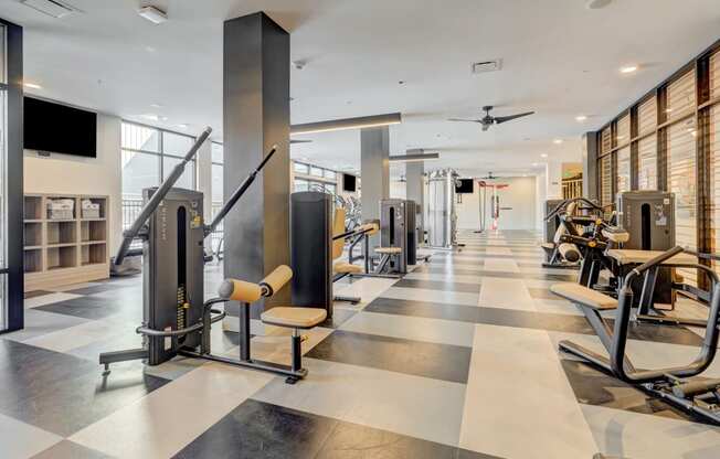 a gym with cardio equipment and a flat screen tv