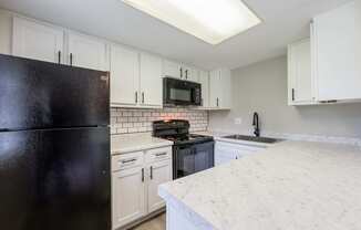 a kitchen with white cabinets and a black refrigerator