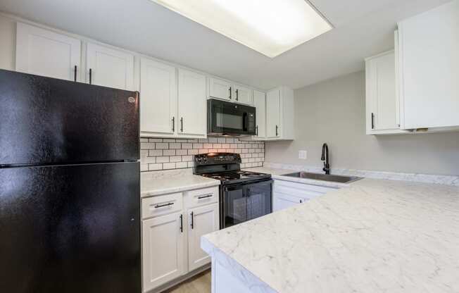 a kitchen with white cabinets and a black refrigerator